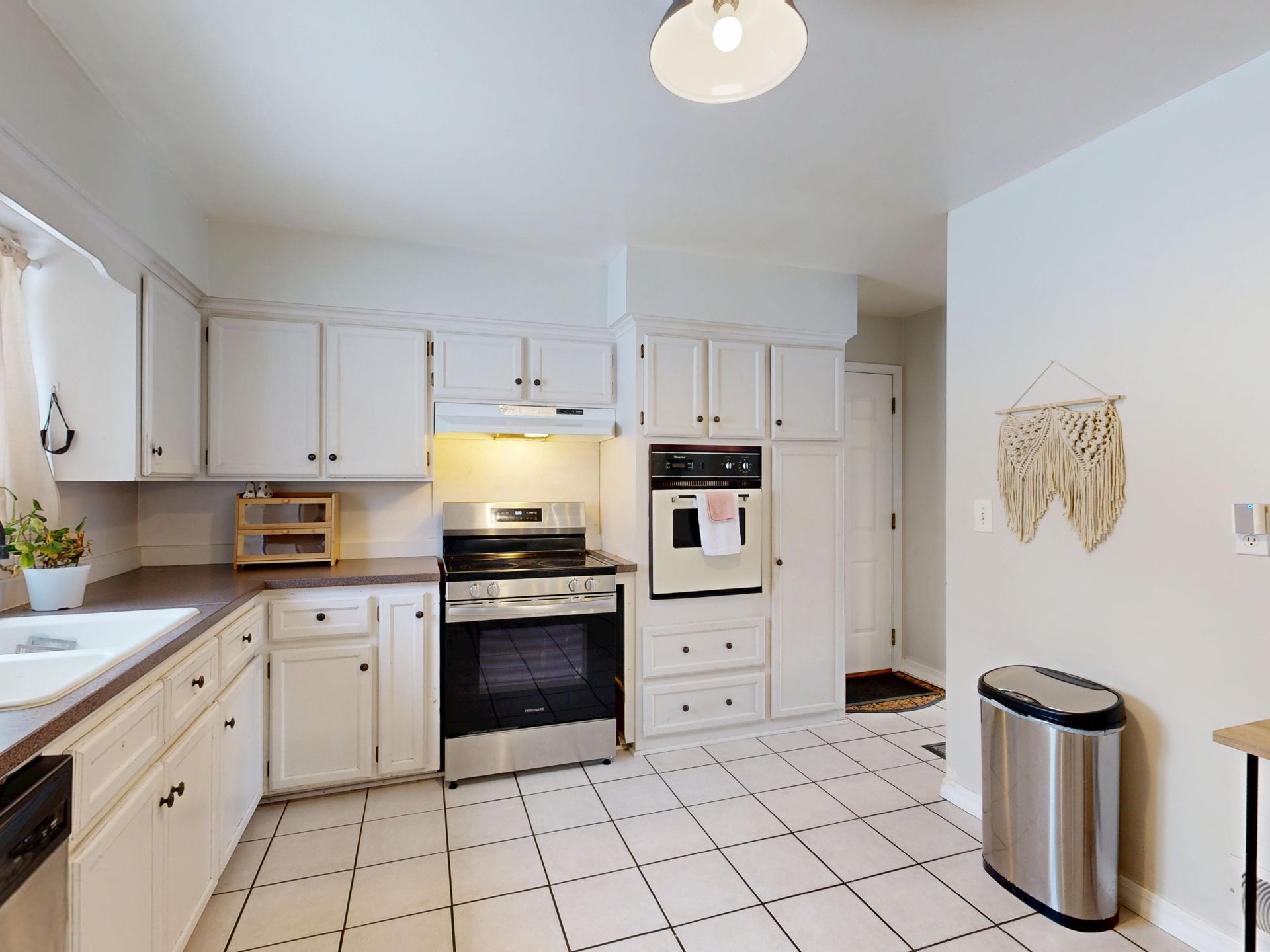 Bright modern white kitchen with stainless steel appliances and tile floor